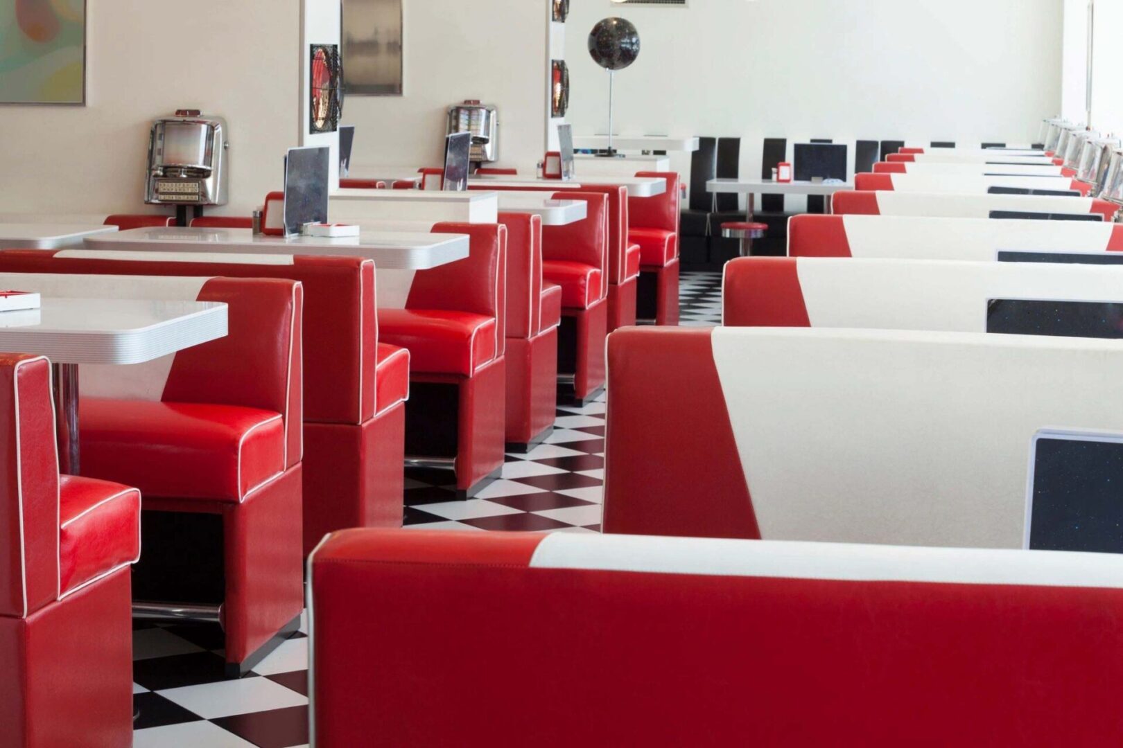 A restaurant with red booths and white tables.